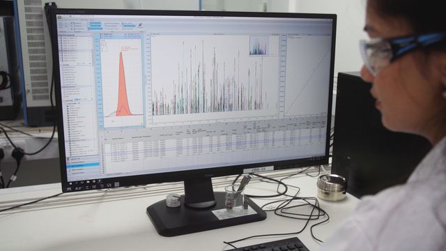 Female scientist working with data using graphs off a computer screen 