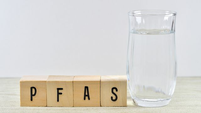A jug of water next to some blocks spelling out the word PFAS. 