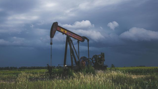 A rusty oil pump extractor in a field on a stormy day. 