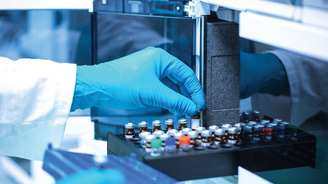 Scientist loading sample vials into a mass spectrometer, highlighting precision in maximizing mass spectrometry output. 