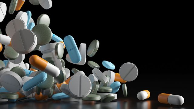 Different types of drug capsules falling across the screen from left to right. 