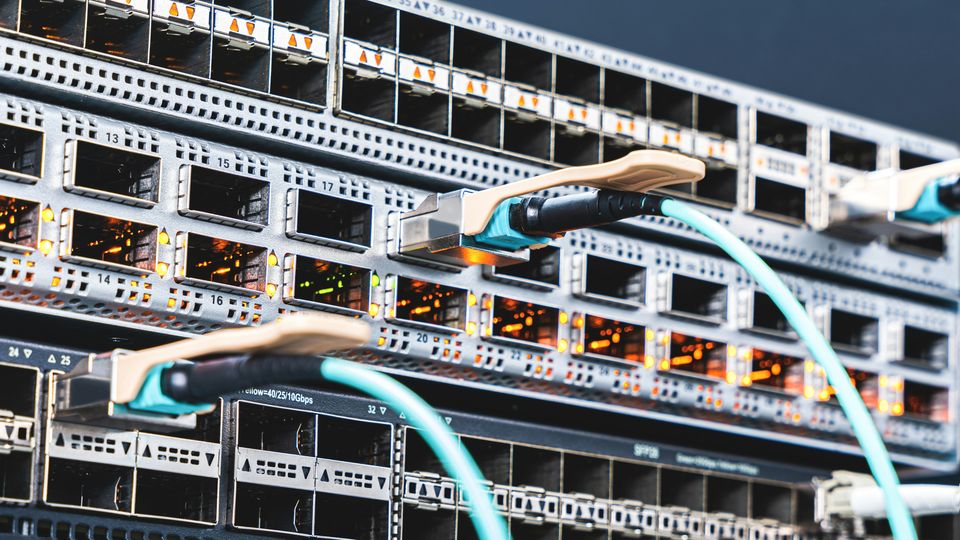 A close-up photo of switches plugged into ports on the side of a large data center server.